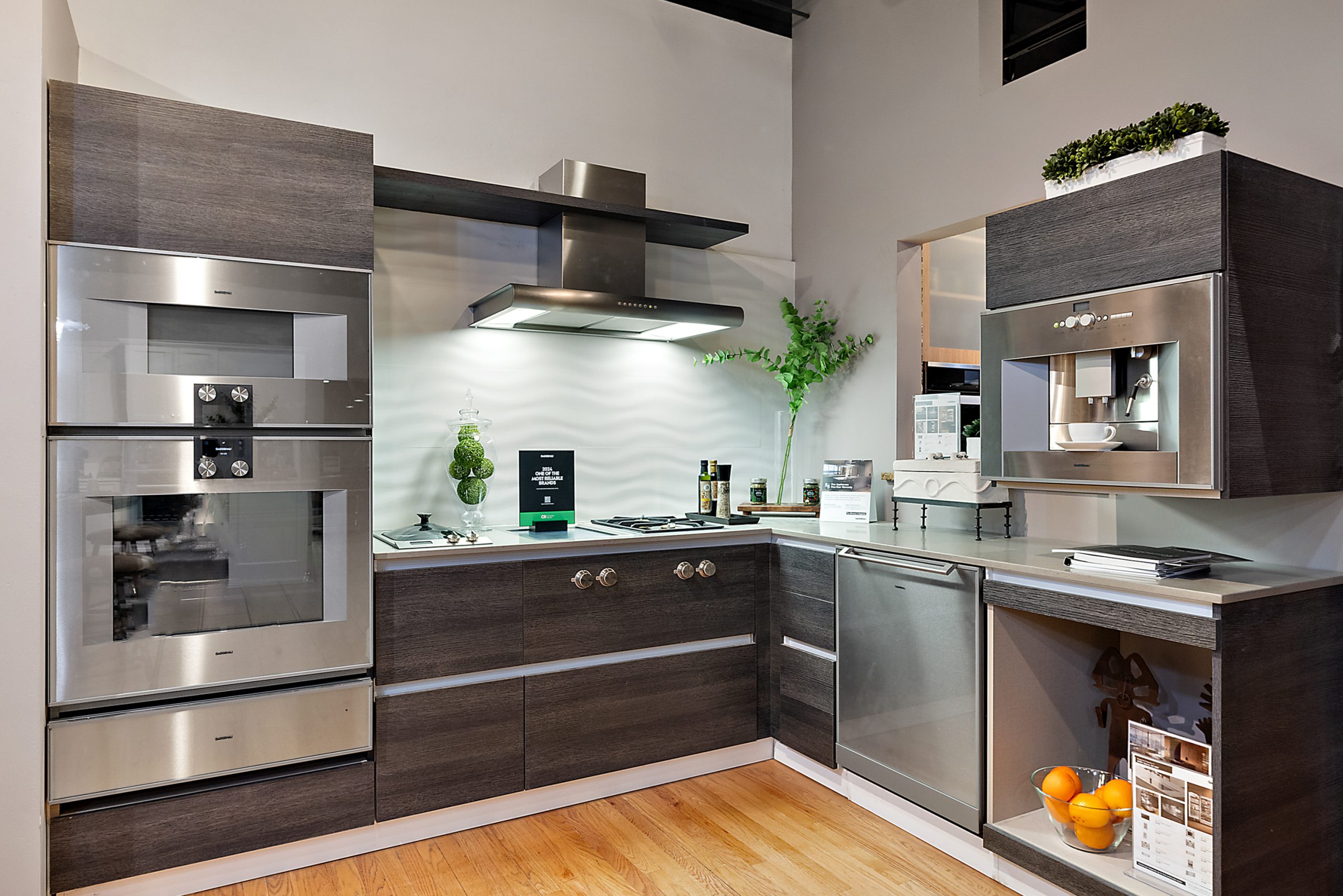 Modern dark wood kitchen display in appliance showroom with stainless steel appliances